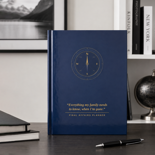 A navy blue hardcover journal titled 'Final Affairs Planner' standing upright on a dark wooden desk. The cover features a gold compass design and a gold quote.